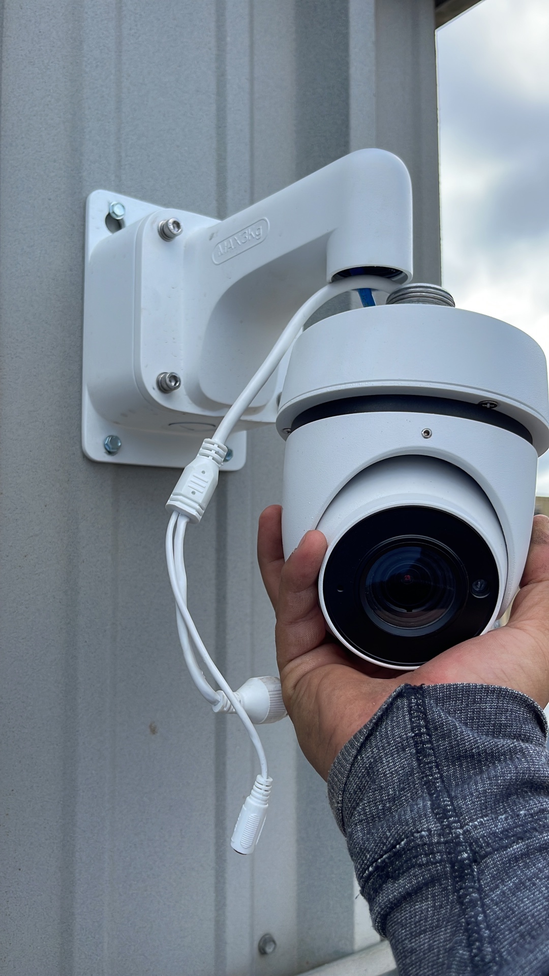 Turret security camera being mounted to a metal building wall with weatherproof connectors